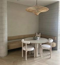 a white table with two chairs and a bowl on it next to a bench in a room