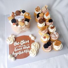 a table topped with lots of cupcakes on top of a white sheet covered in frosting