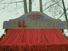 a sign that says kissing booth with red drapes on the front and side of it