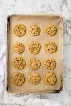 twelve cookies on a baking sheet ready to go into the oven, with crumbs all over them