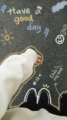 someone's feet on the ground with chalk drawings and words written on it in front of them