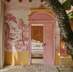 an open door leading to a bedroom with pink walls and paintings on the wall behind it