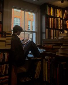 a person sitting in front of a window with books on the shelves and looking out