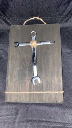 a wooden sign with two wrenches hanging from it's side on a black background