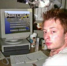 a young man sitting in front of a computer monitor with the word minecraft on it