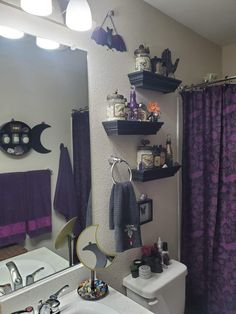 the bathroom is decorated with purple and black decor, including shelves on the wall above the toilet