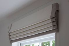 a close up of a window with the blinds pulled back to reveal pleated drapes