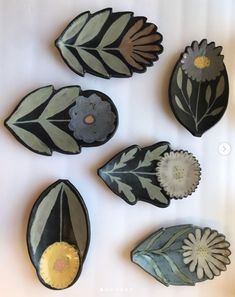 five decorative plates with flowers and leaves on them, all in different shapes and sizes