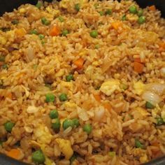 a pan filled with rice, peas and carrots