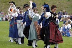 several people dressed in historical clothing dancing on the grass