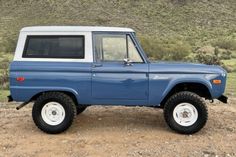 a blue and white truck parked on top of a dirt field