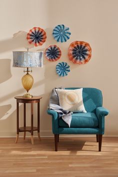 a blue chair sitting next to a table with a lamp on top of it in front of a white wall