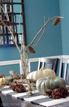 a dining room table with pine cones and pumpkins