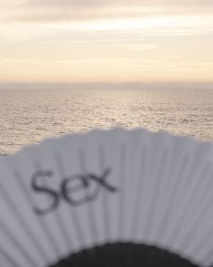 a fan sitting on top of a beach next to the ocean under a cloudy sky