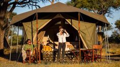 two men are standing in front of a tent while one man is taking a photo