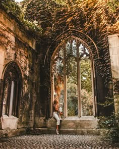 a woman is sitting in an old building with ivy growing on the walls and windows