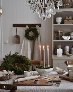 a dining room table with candles and other items on the table, including wreaths