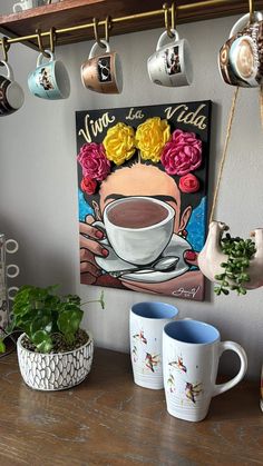 there is a coffee cup on the table with two mugs next to it and some plants