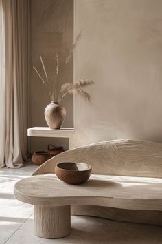 a wooden bowl sitting on top of a table next to a vase