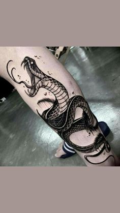 a black and white tattoo with a snake on it's leg, in the middle of