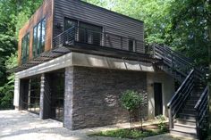 a modern house in the woods with stairs leading up to it's second story