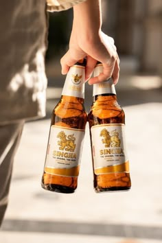 two bottles of beer being held by someone