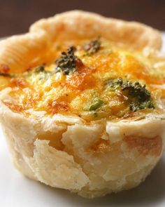 a quiche with broccoli and cheese on top sits on a white plate