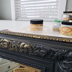 some jars are sitting on top of a black table with gold trim around the edges