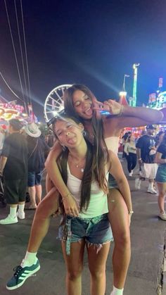 two girls are posing for the camera at an amusement park