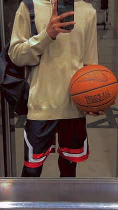 a man taking a selfie in front of a mirror holding a basketball