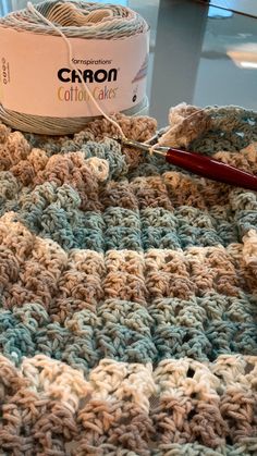 a crocheted blanket with yarn and scissors on it