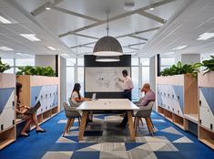 people are sitting at a table in an office with blue carpeting and white walls