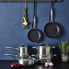 pots and pans are hanging on the wall next to each other with vegetables in them