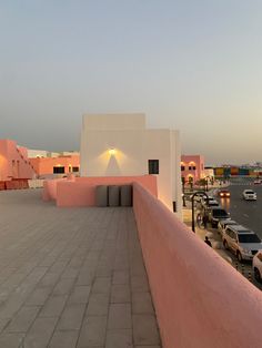 cars are parked on the side of a building near a parking lot with pink and white walls