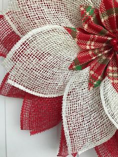 a red and white christmas wreath with burlocked flowers on it's side