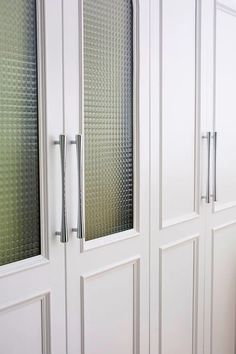 the interior of a kitchen with white cabinets and glass door handles on each side of the doors