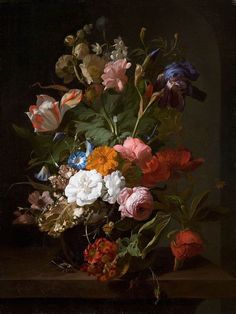 a vase filled with lots of colorful flowers on top of a wooden table next to a black wall