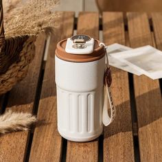 a white and brown cup sitting on top of a wooden table next to a basket