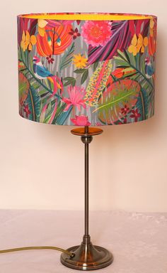 a lamp that is on a table with a flower print lampshade next to it