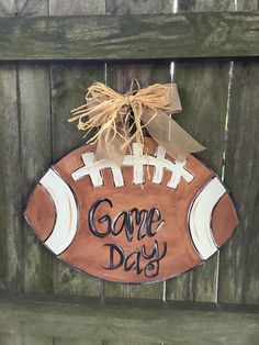 a wooden sign that says game day hanging on a fence