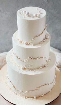 a three tiered white wedding cake with pearls