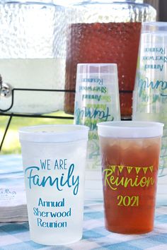 plastic cups with names on them sitting on a checkered tablecloth in the sun