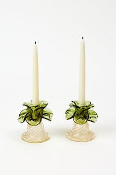 two white candles with green flowers on them