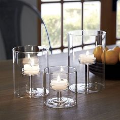 candles are placed in clear glass holders on a table