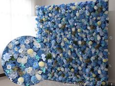 blue and white flowers are arranged on the wall next to a round object that looks like it has been made out of paper