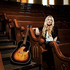 a woman sitting in a church with an acoustic guitar