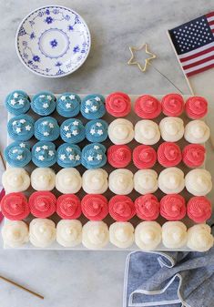 an american flag cake with red, white and blue cupcakes in the middle