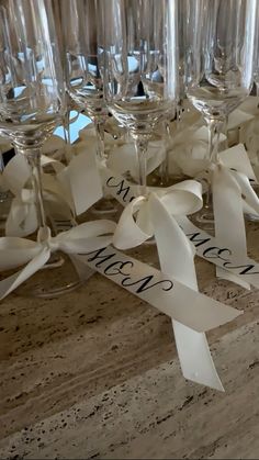 several wine glasses with white ribbons on them