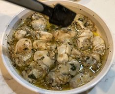 a bowl filled with chicken and broth on top of a table next to a spoon