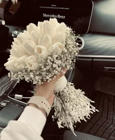 a person holding a bouquet of flowers in their hand while sitting in a car seat